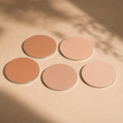 Five round makeup powder pans in neutral tones