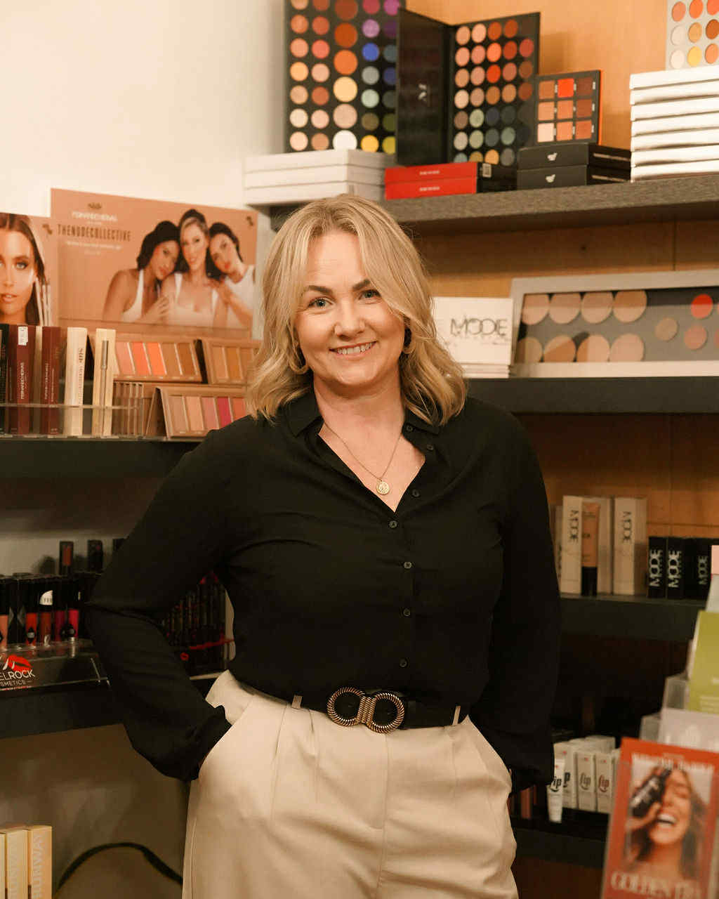 Woman smiling in a makeup store setting.